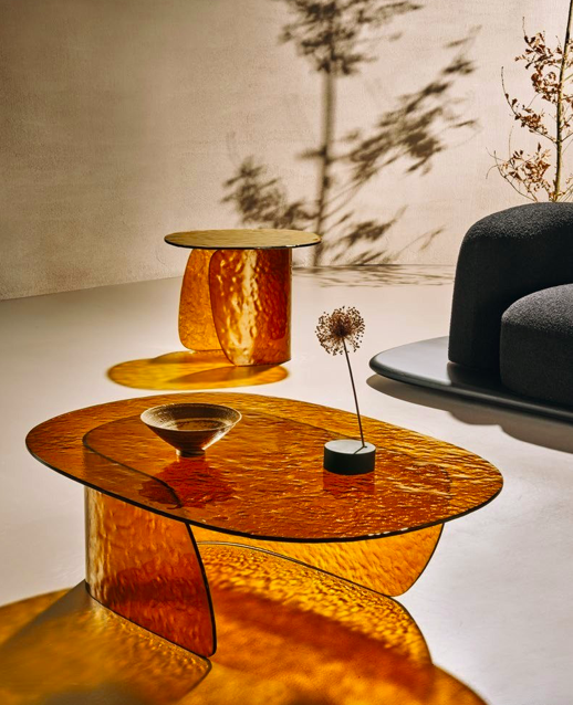 Tables basses et d’appoint en verre ambré texturé au design contemporain, projetant des reflets lumineux dans un intérieur moderne.