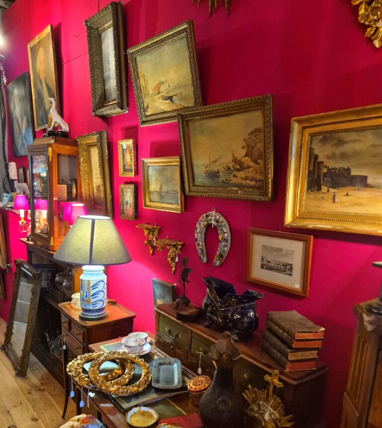 Intérieur d'antiquaire chargé avec mur fuchsia et cadres anciens — avant de repenser entièrement son intérieur