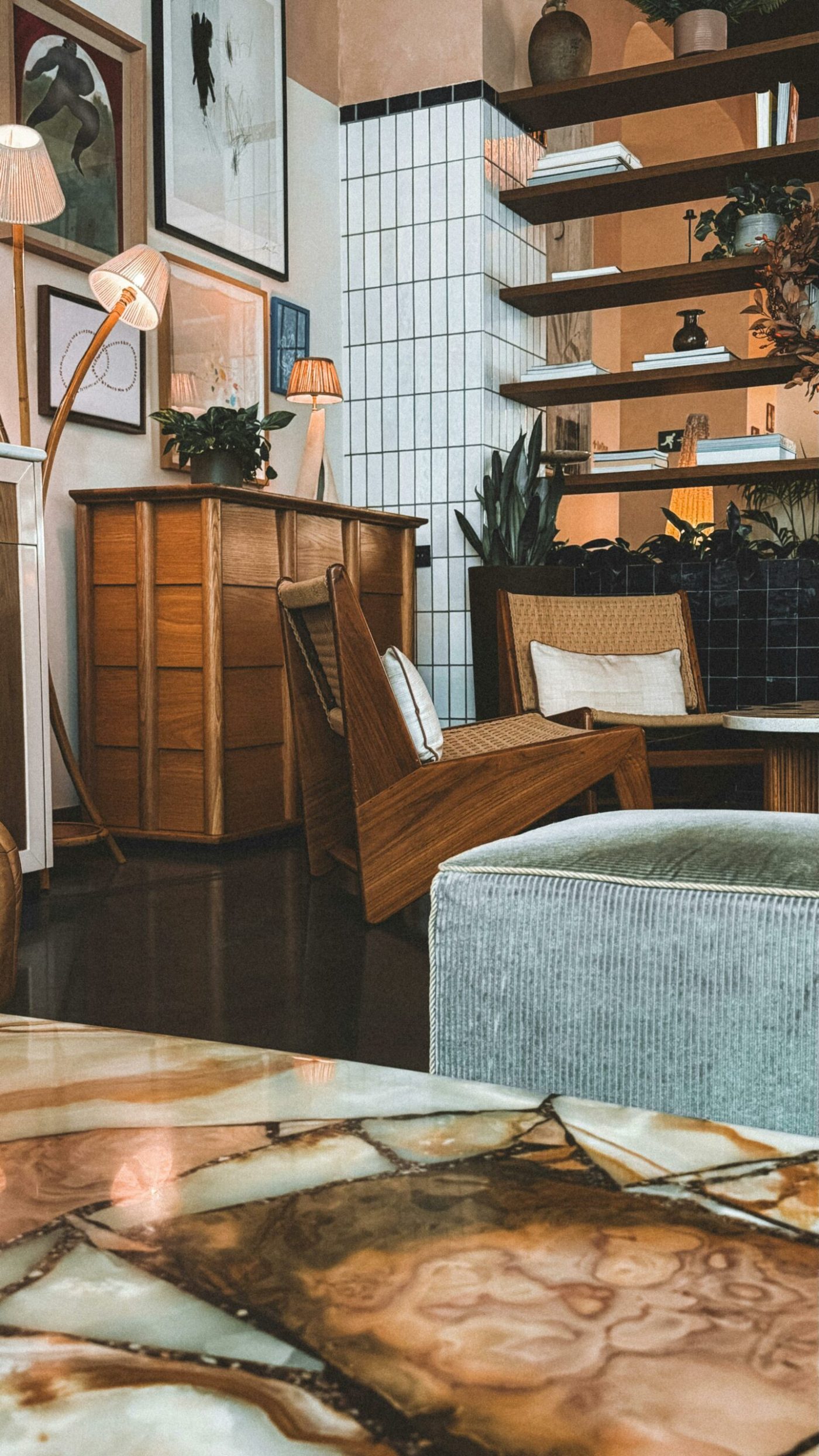 Salon esprit mid century avec fauteuil, mobilier en bois et étagères murales baignées de lumière naturelle.